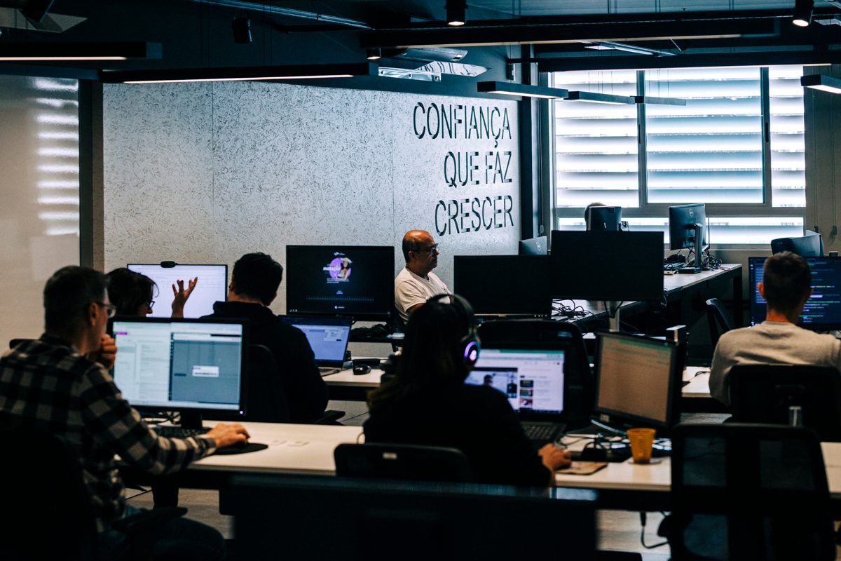 Equipe Consistem trabalhando no escritório, com a frase 'Confiança que faz crescer' na parede